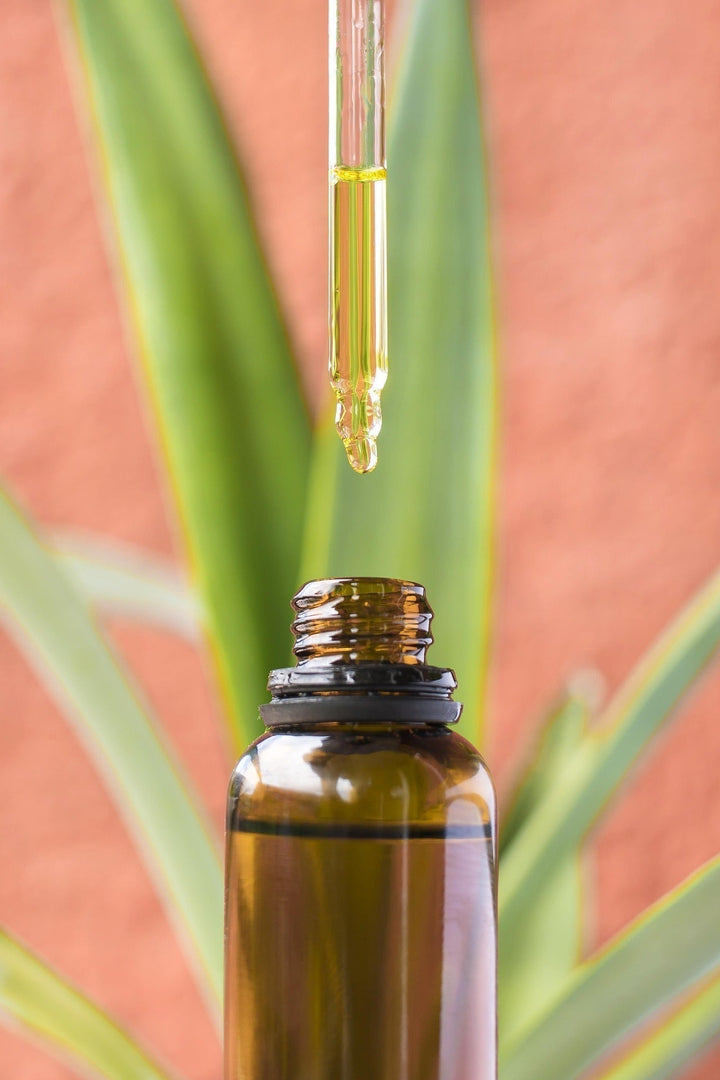 Das Bild zeigt eine Pipette, aus der ätherisches Ingweröl in eine Flasche tropft